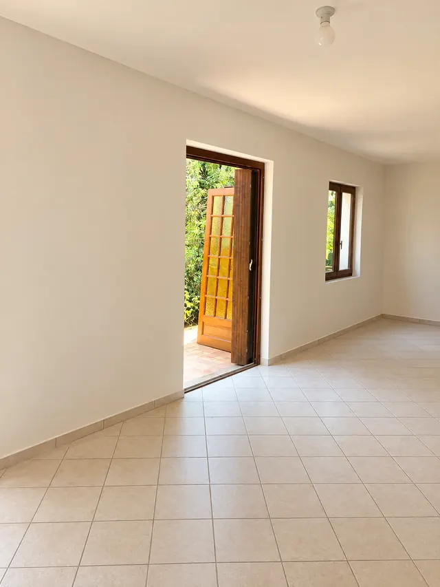 Le même mur terminé : surface lisse peinte en blanc, embrasure enduite autour de la porte vitrée