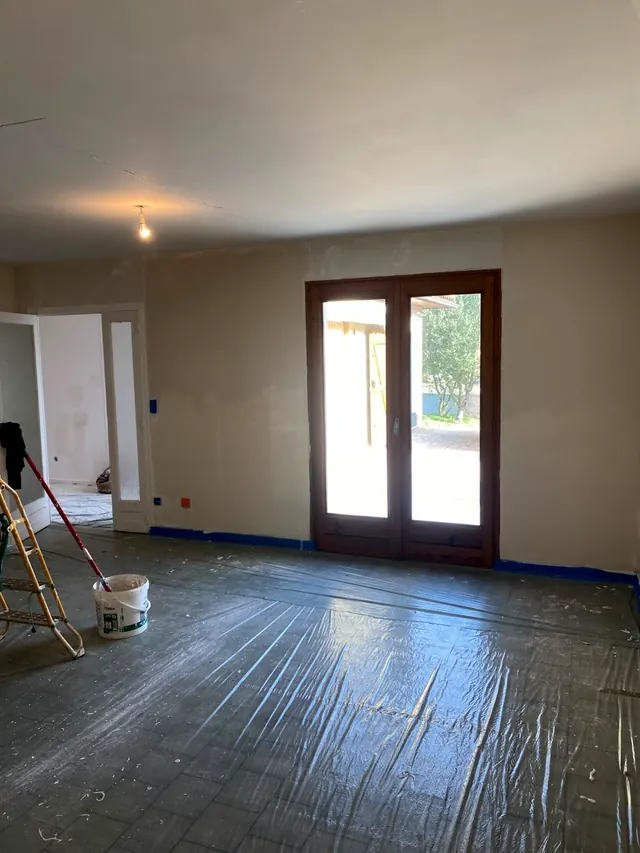 Pièce en rénovation : reprises d’enduit sur les murs et le plafond, sol sous bâche, avant le ponçage