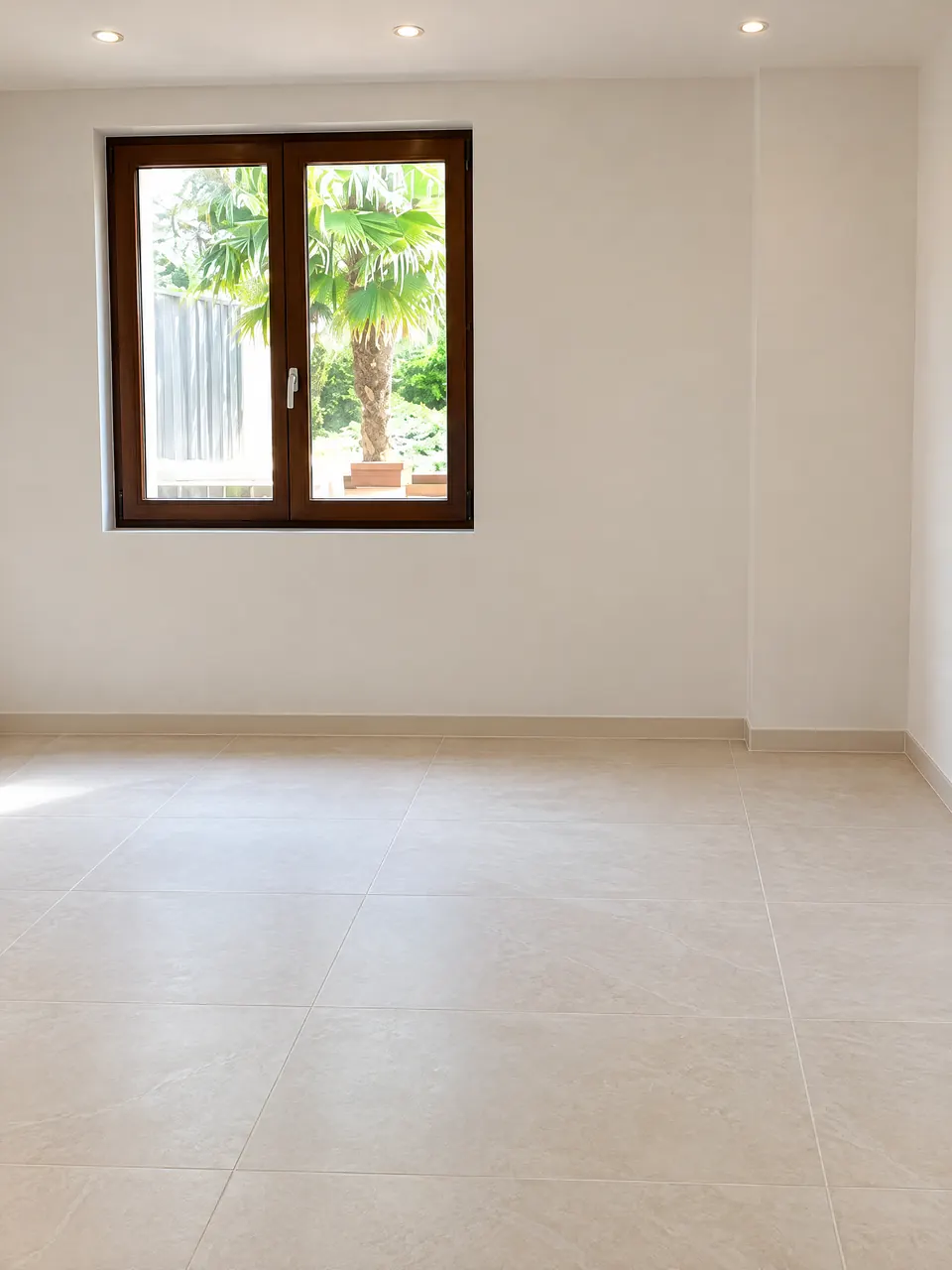 Pièce terminée avec un plafond blanc lisse, murs blancs, fenêtre en bois donnant sur un palmier