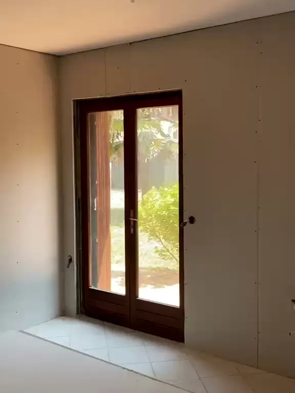 Pièce fermée en plaques de plâtre vissées, porte-fenêtre en bois sur le jardin, avant les bandes