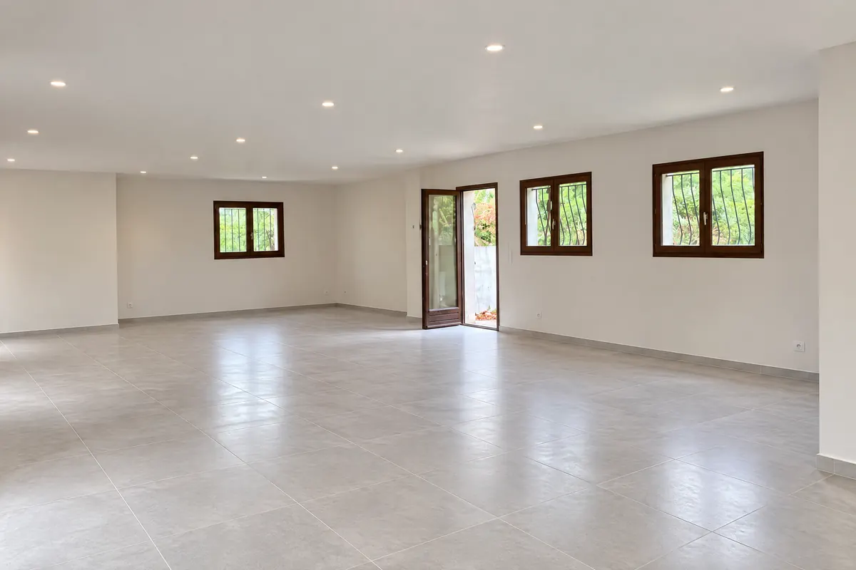 Rez-de-chaussée rénové : plafond blanc, murs lisses, carrelage gris clair, fenêtres en bois