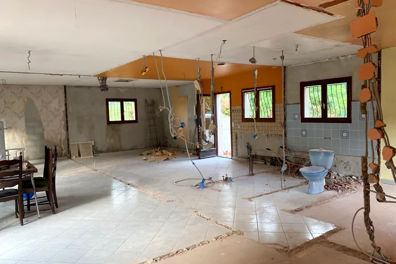 Rez-de-chaussée en dépose : ancien plafond orange en partie déposé, câbles qui pendent, papier peint arraché