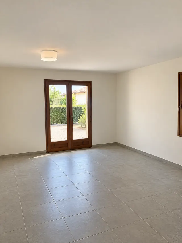 Le même séjour terminé : murs et plafond blanc cassé, porte-fenêtre en bois