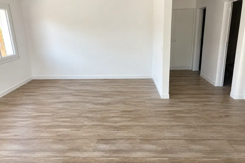 La même pièce terminée : carrelage imitation bois jointé, plinthes blanches, murs peints